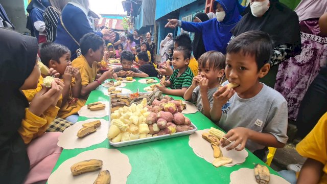Anak-anak di Kecamatan Ujung Tanah mengonsumsi makanan yang di rebus bersama dengan DPPPA Makassar, Minggu (27/3).