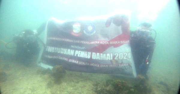 Damkar Makassar Bentangkan Bendera Pemilu Damai di Kedalaman 12 Meter Pulau Samalona