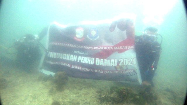 Damkar Makassar Bentangkan Bendera Pemilu Damai di Kedalaman 12 Meter Pulau Samalona