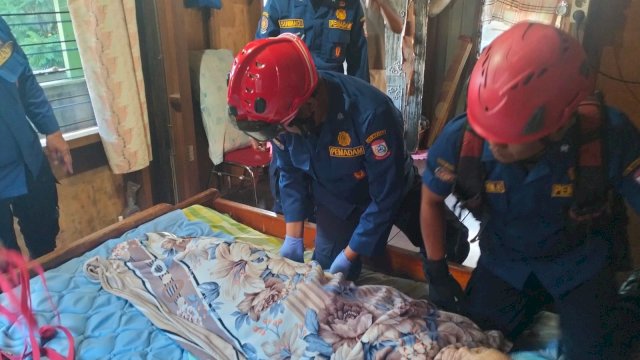 Petugas Damkarmat Kota Makassar mengevakuasi seorang lansia yang akan di bawa ke rumah sakit di Jalan Sunu, Rabu (21/8) || istimewa 